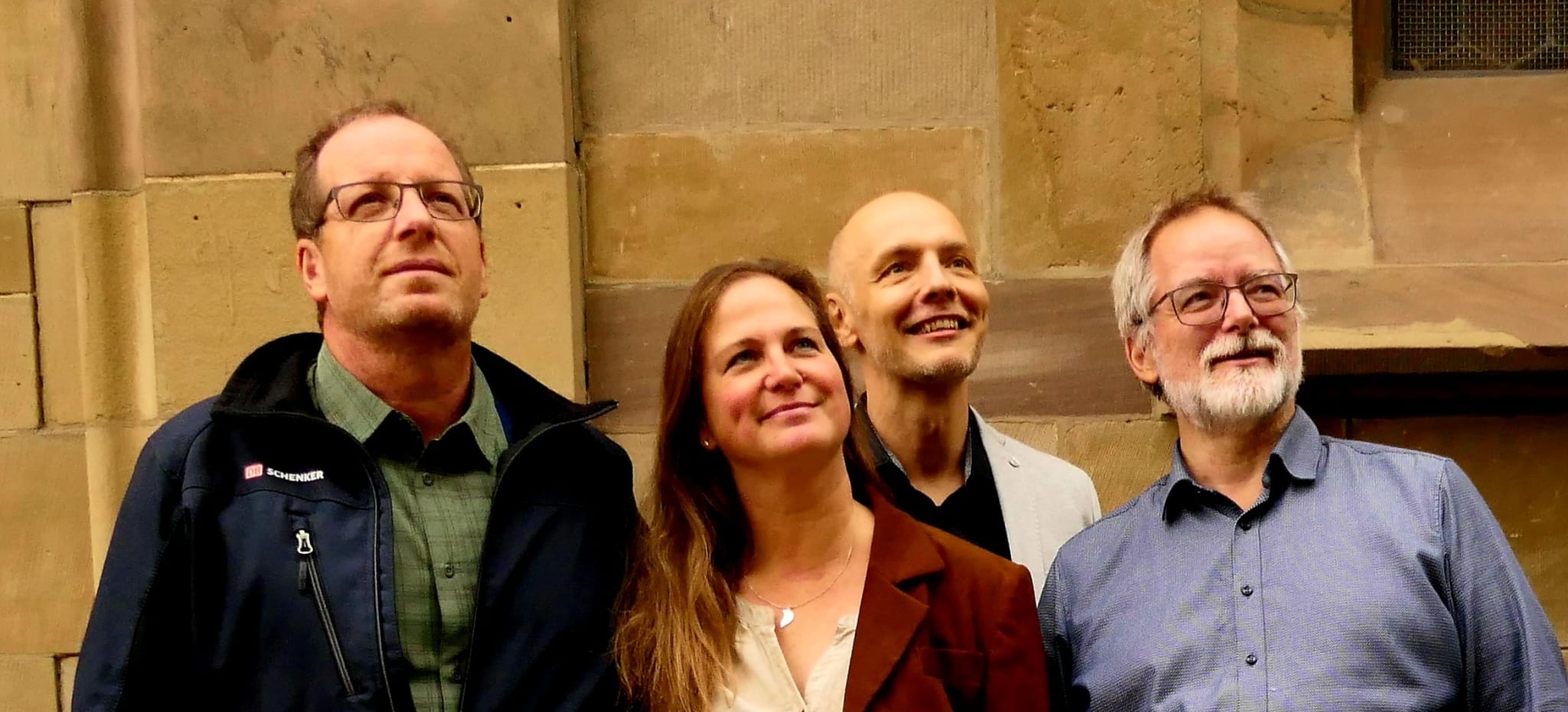 Die Mitglieder der Band stehen vor einer Kirche und schauen vom Betrachter aus gesehen nach rechts oben. Von links nach rechts: Klaus Fiedler, Sandra Fiedler, Martin Thys, Heiko Kuschel